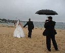 Newlyweds stroll on the rainy beach after a ceremony stating lifetime commitment.